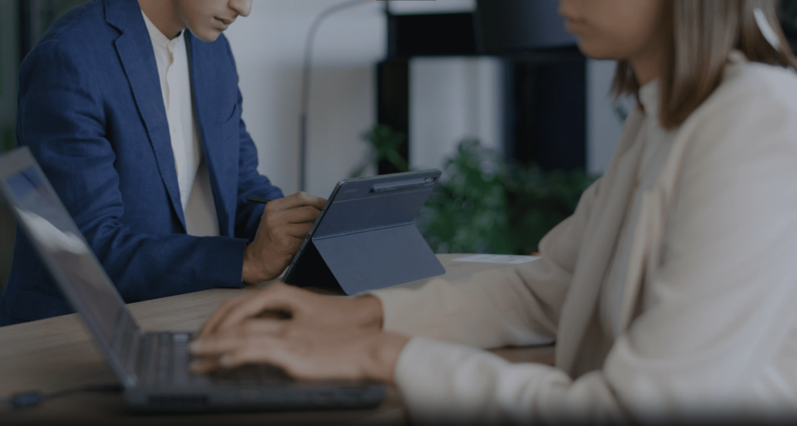 Two people working, one on a laptop and one on a tablet.